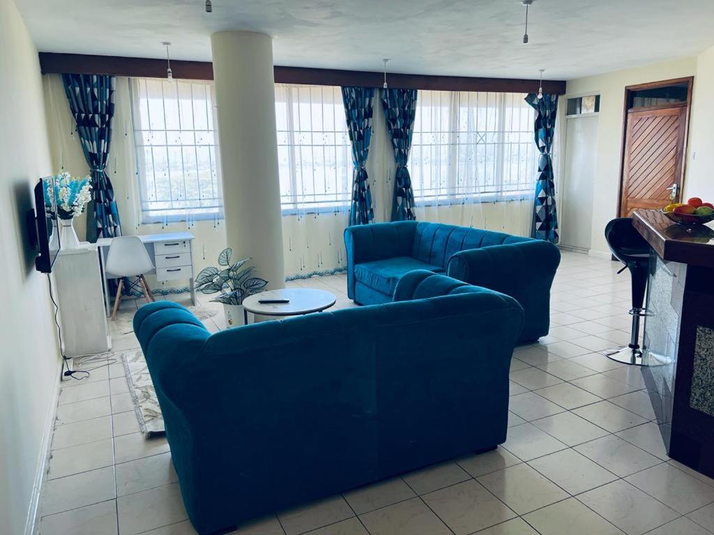 un soggiorno con 2 divani blu e un tavolo di Swan Lakeview 2 Apartment with WiFi,Netflix Free Parking,Sunset,Lakeview a Kisumu
