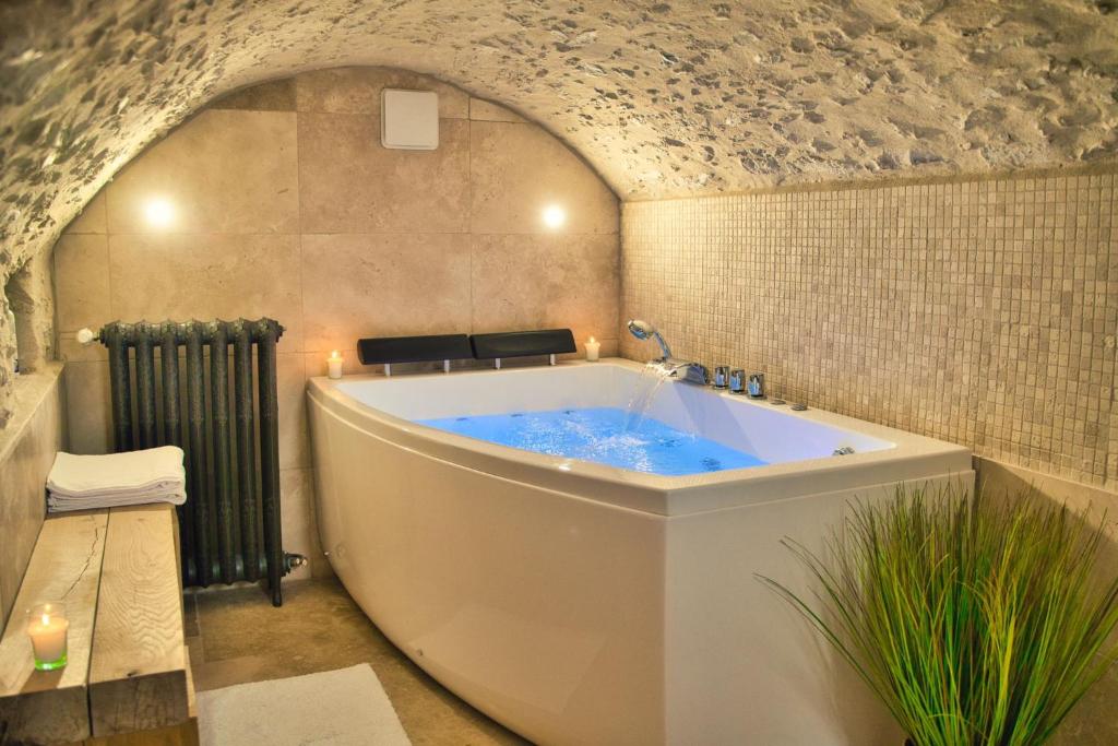 a bath tub in a bathroom with a stone wall at L’Oxalis villa, Sauna et Jaccuzi privatif in Bullion