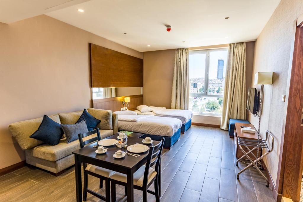 um quarto de hotel com uma cama, um sofá e uma mesa em The Seventh Star Hotel Suites em Amã
