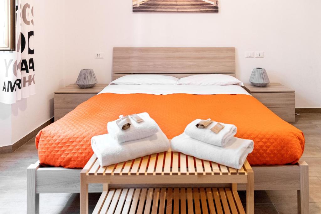 - un lit orange avec 2 serviettes sur un banc dans l'établissement Sannio Deluxe Apartment - San Giovanni, à Rome