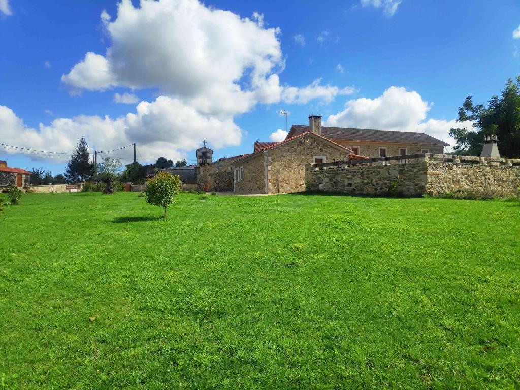 un patio verde con una casa y una pared de piedra en Casa Rural Casa Cancela, en Esfarrapa