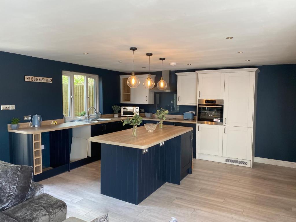 a kitchen with white cabinets and a blue wall at Oak Bray Coach House in Bray