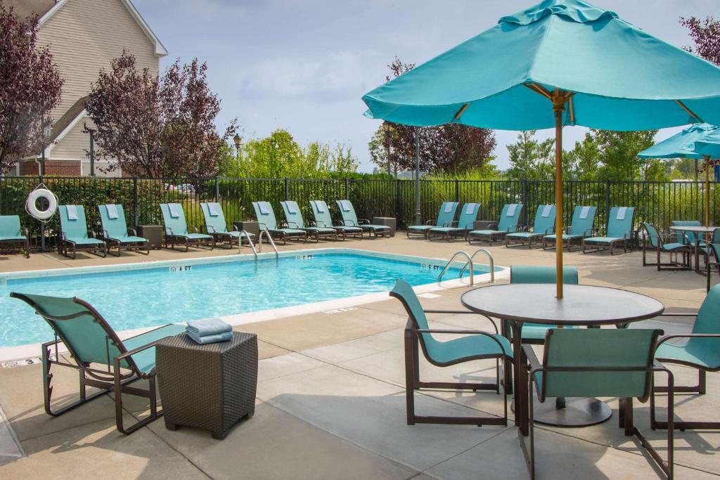 a pool with chairs and a table with an umbrella at Sonesta ES Suites Charleston in Charleston