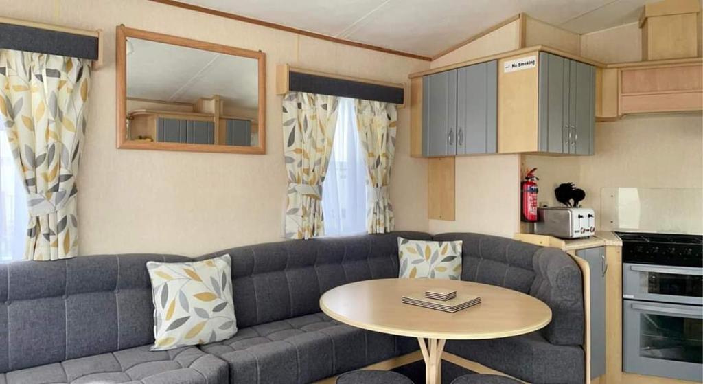 sala de estar con sofá y mesa en dees caravan lettings kingfisher elm 453, en Ingoldmells