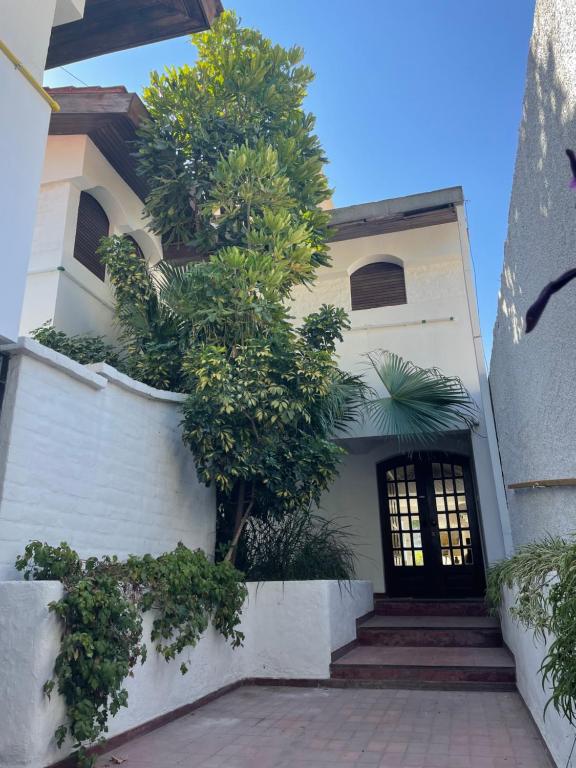 uma casa branca com uma porta preta e uma árvore em Arístides Lodge em Mendoza