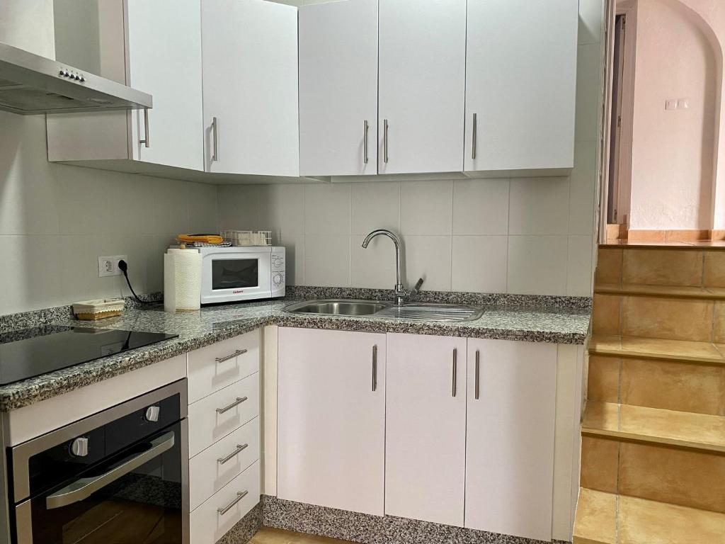 a kitchen with white cabinets and a sink and a microwave at APARTAMENTO ARACENA RURAL in Aracena