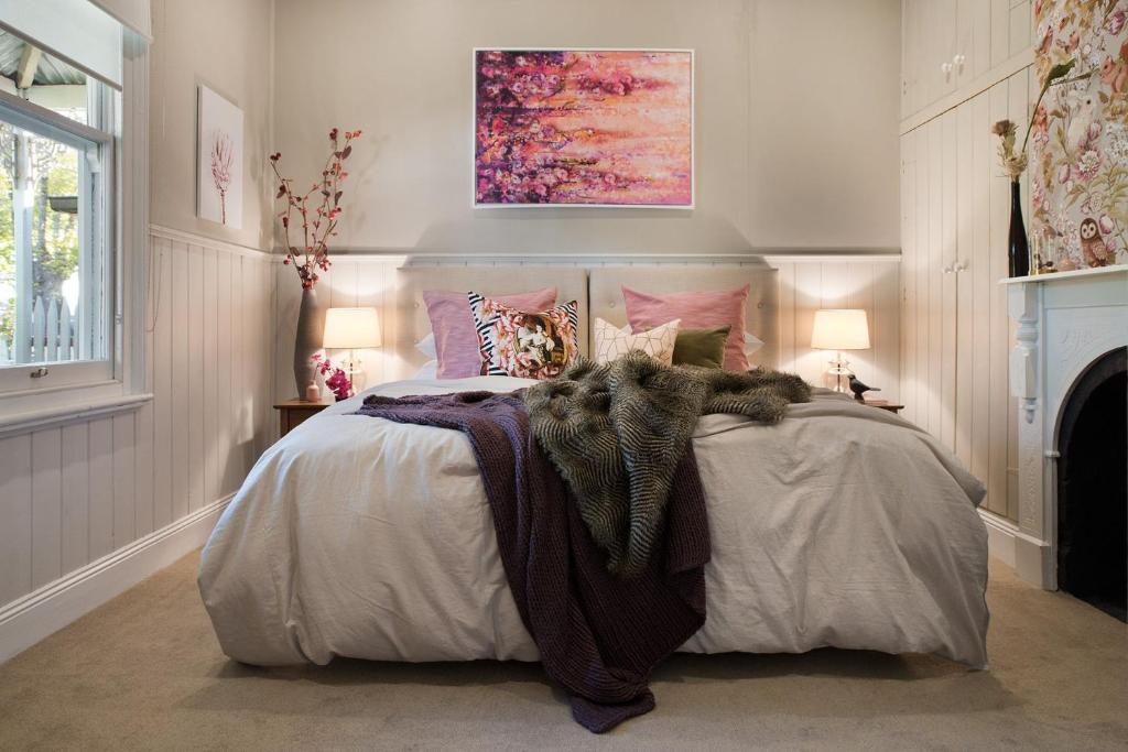 a bedroom with a large bed with pink and purple pillows at Albert Cottage in Daylesford