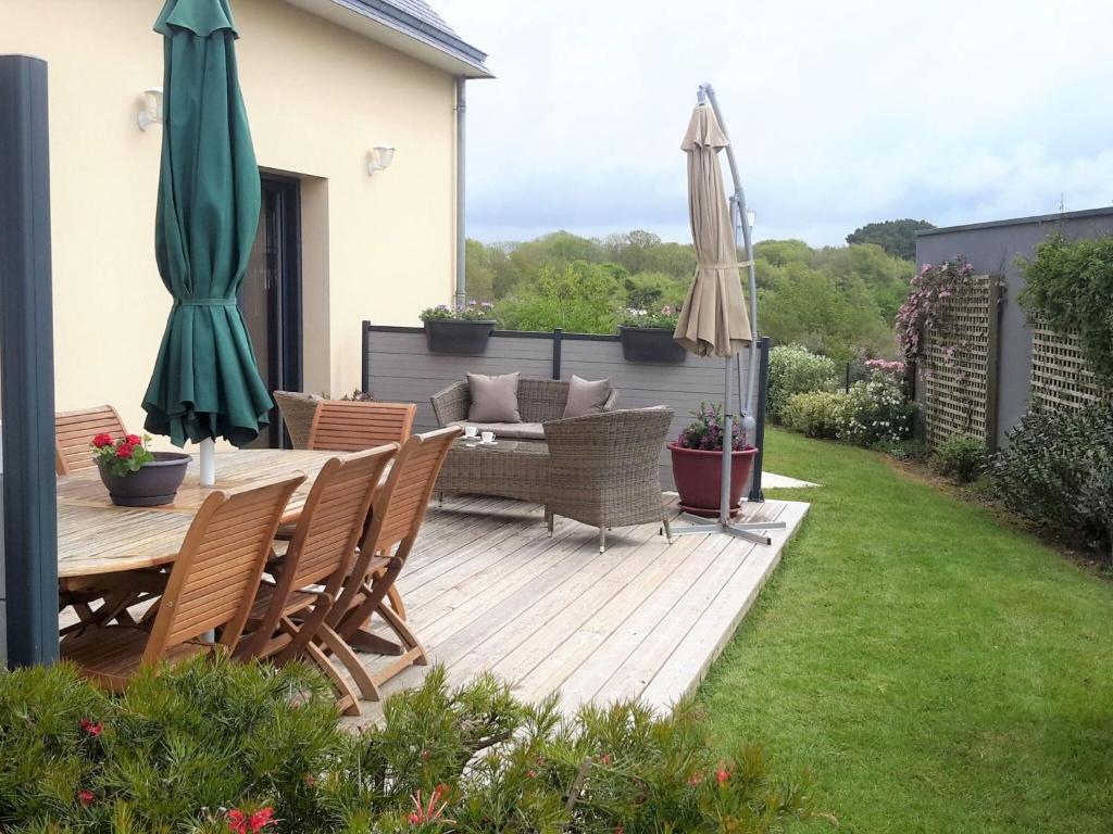 una terraza de madera con mesa, sillas y sombrillas en Cottage, Le Pouldu, en Le Pouldu