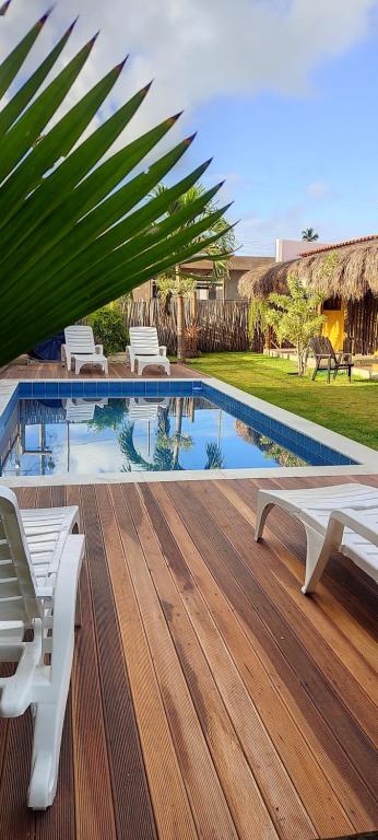 a swimming pool with a wooden deck with chairs and a pool at Reserva Rede e Mar - Rota dos Milagres - Patacho in Pôrto de Pedras