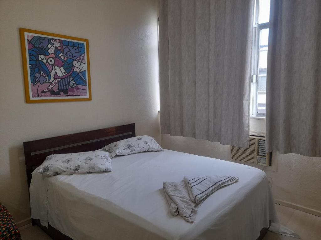 Schlafzimmer mit einem Bett mit weißer Bettwäsche und einem Fenster in der Unterkunft santa clara 1003 in Rio de Janeiro