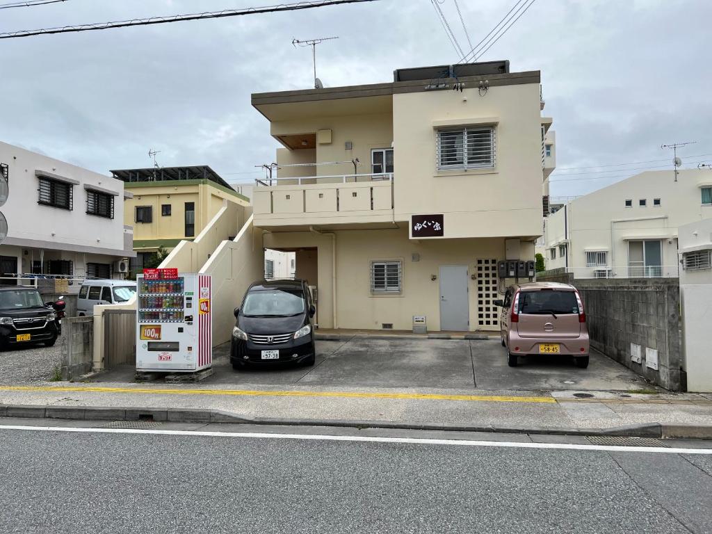 two cars parked in a parking lot in front of a building at ゆくい家 in Ginowan