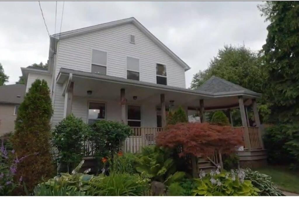 a white house with a porch and some plants at Garden 2 Storey House in Niagara Falls