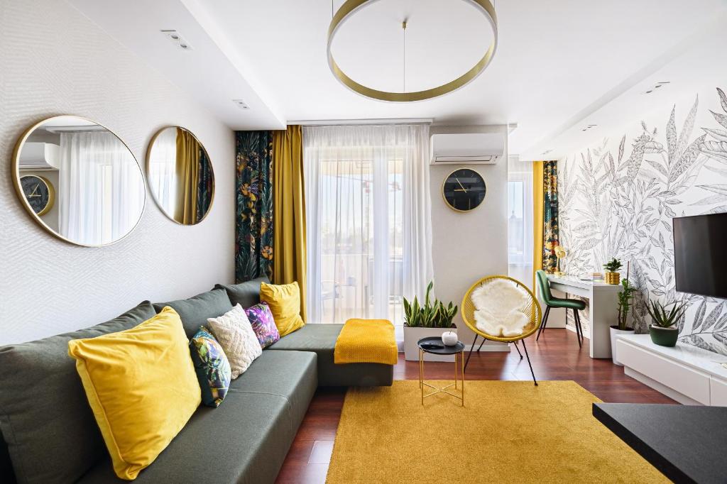 uma sala de estar com um sofá verde e almofadas amarelas em HÍD19 APARTMAN GYŐR BELVÁROS-FREE PARKING-TERRACE az RQ VÍZI ÉLMÉNYPARK ÉS GYÓGYFÜRDŐNÉL em Gyor