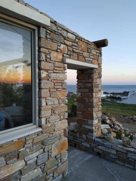 a window in a brick wall with a view of the ocean at Enalion residences in Tinos