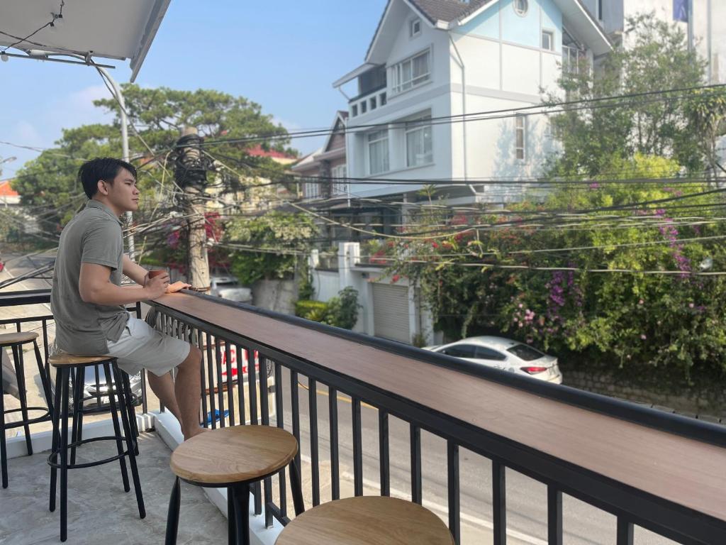 Ein Mann, der auf einem Balkon an einer Bar sitzt. in der Unterkunft CT Home in Da Lat