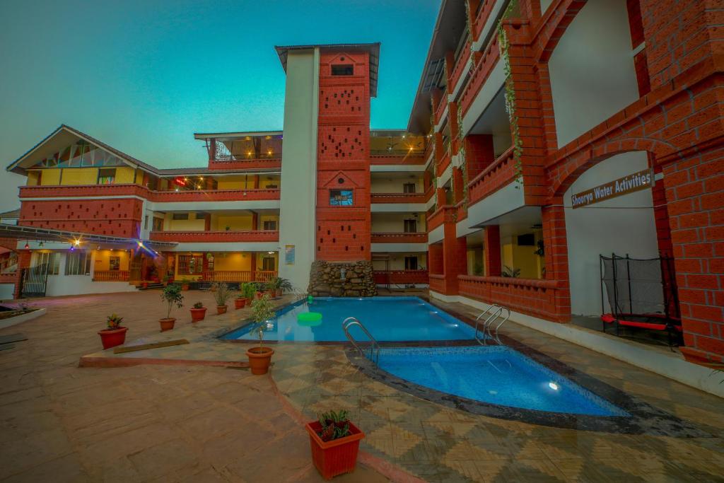 een hotel met een zwembad op een binnenplaats bij Ansh Resort, Dandeli in Dandeli