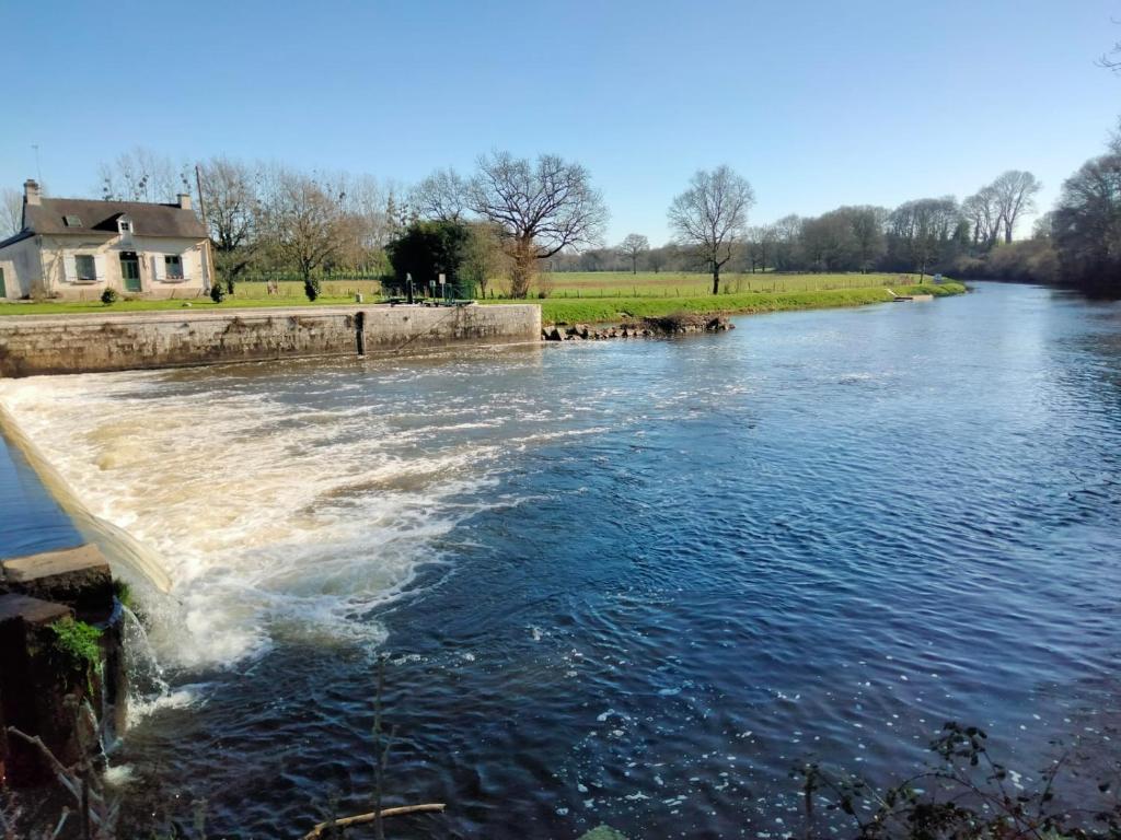 Un río con agua saliendo de una presa en Hébergement canal, en Villeder