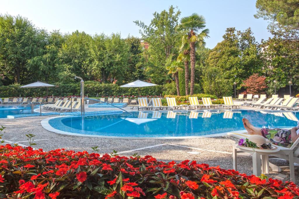 una piscina con sillas y flores en un complejo en Hotel Bristol Buja, en Abano Terme