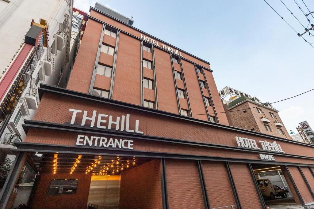 Hotel the Hill في غوانغجو: مبنى من الطوب الأحمر طويل مع علامة على مدخل التل