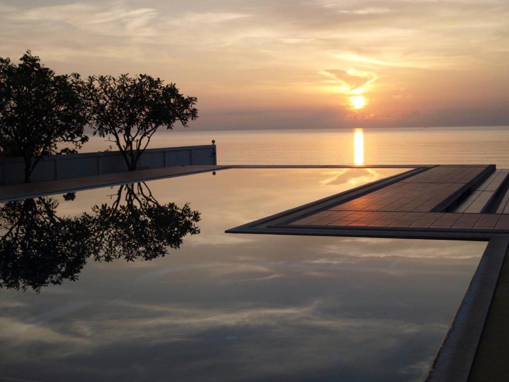 a swimming pool with the sunset in the background at 2-Bedroom Khanom Beach Ocean Front Condo in Khanom