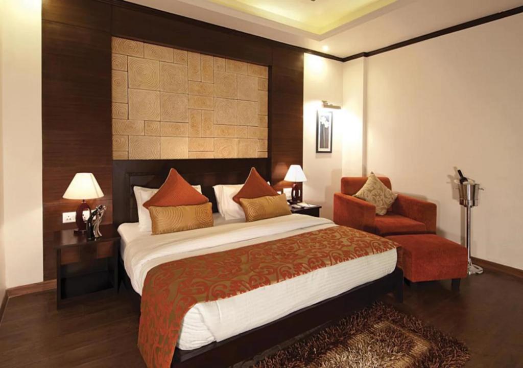 una habitación de hotel con una cama grande y una silla en Hotel Comfort Inn Bl, en Bareilly