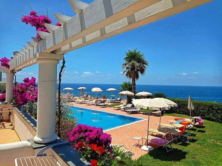a swimming pool with umbrellas and chairs and the ocean at Hotel Albatros in Ischia