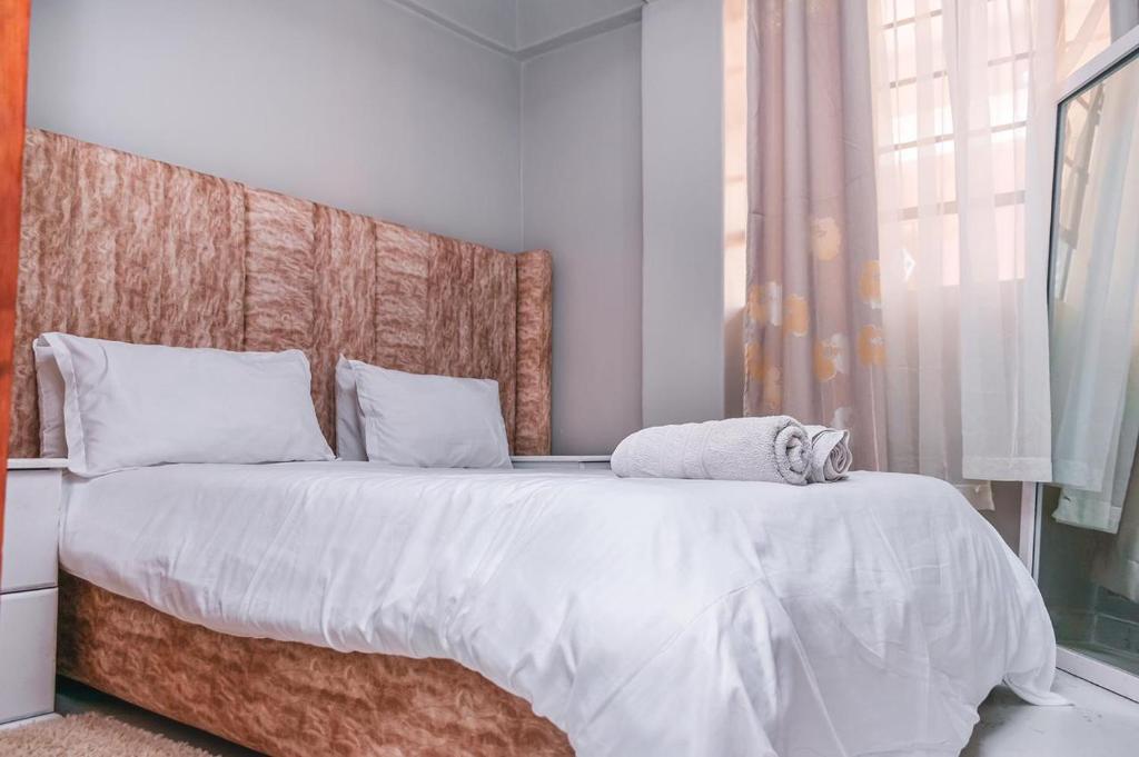 sypialnia z dużym łóżkiem z drewnianym zagłówkiem w obiekcie Stay.Plus Oark Apartment Kisii w mieście Kisii