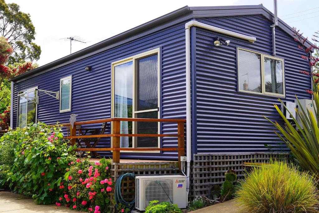 een blauw tiny house met een veranda en bloemen bij 19 Blue in Kingston Beach