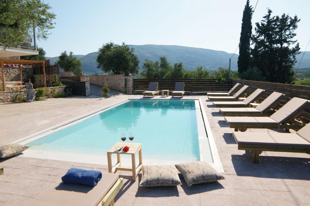 a swimming pool with lounge chairs and a table at Manoir Dennise Villa in Zakynthos