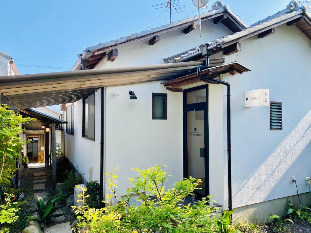 una casa blanca con una puerta grande en un patio en Backpackers Hostel TSUBAMENOYADO, en Shizuoka