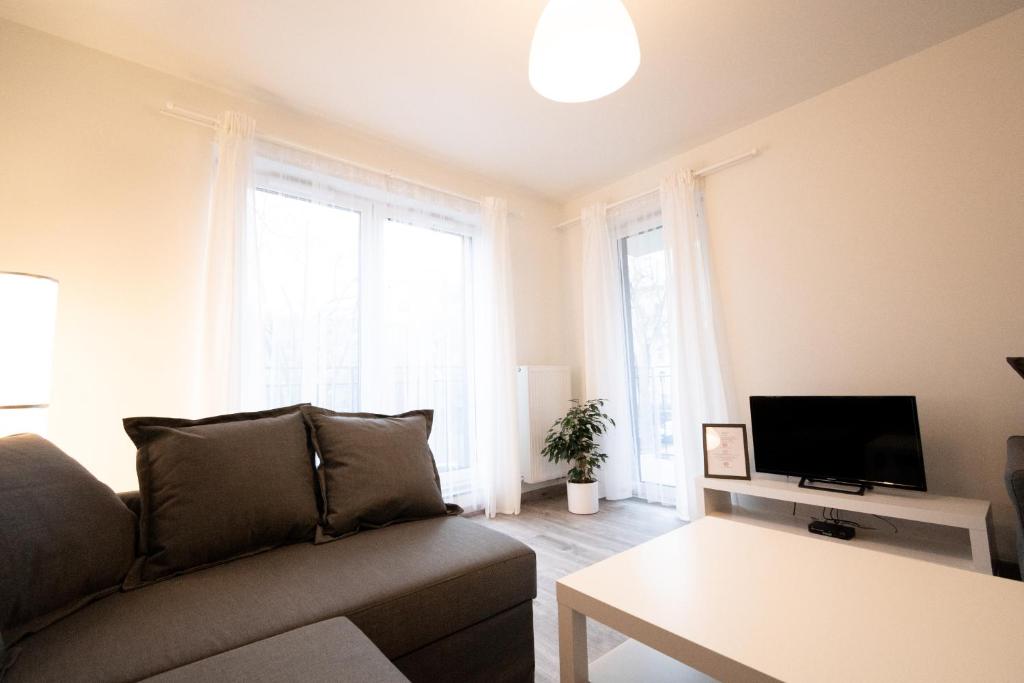 - un salon avec un canapé et une télévision dans l'établissement Apartament Bravo, à Łódź