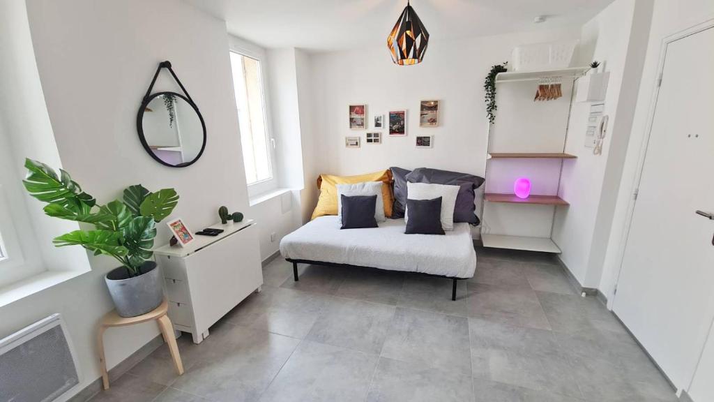 Cette chambre blanche dispose d'une chaise et d'un miroir. dans l'établissement MaxBnb - Studio Cozy - Climatisé - WiFi Fibre - 10 min à pied Gare -3-, à Toulon