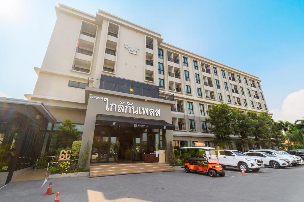 a building with a scooter parked in a parking lot at Glai Gan Place Hotel in Sara Buri