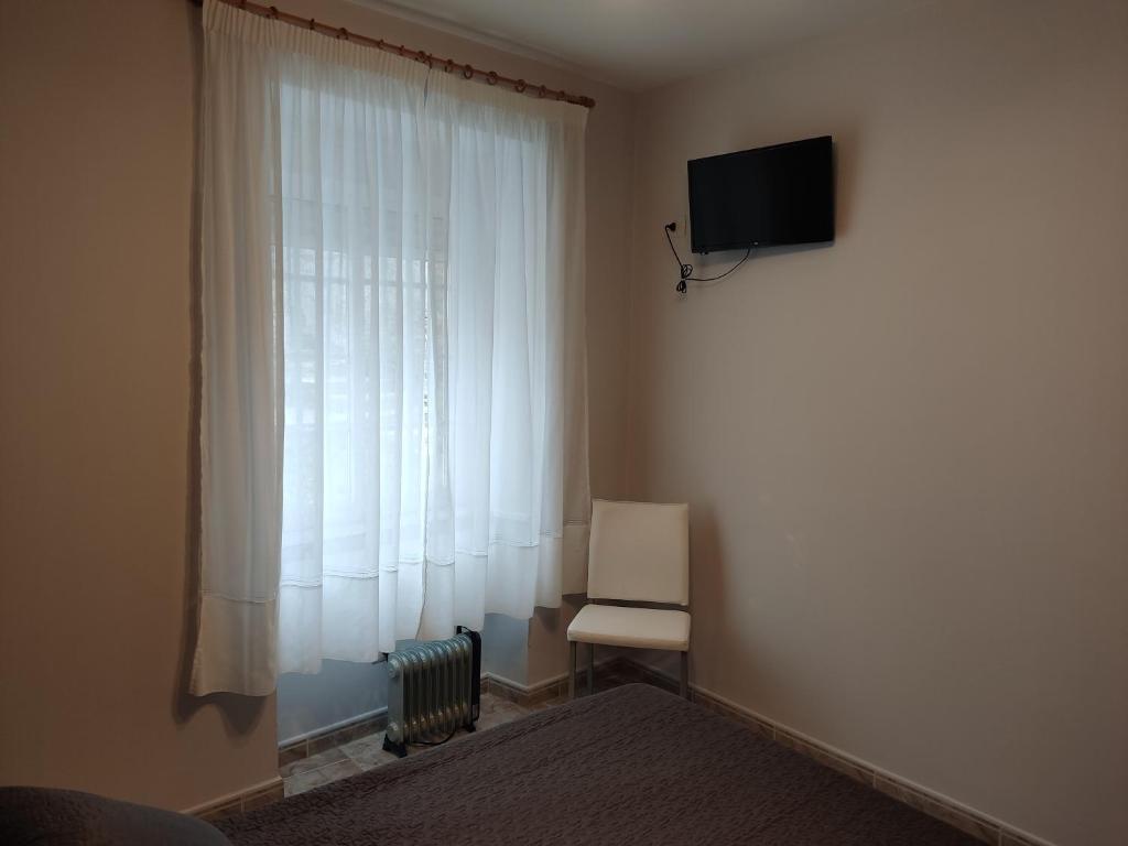 a room with a window with a chair and a television at OS MUIÑOS in Ribadeo