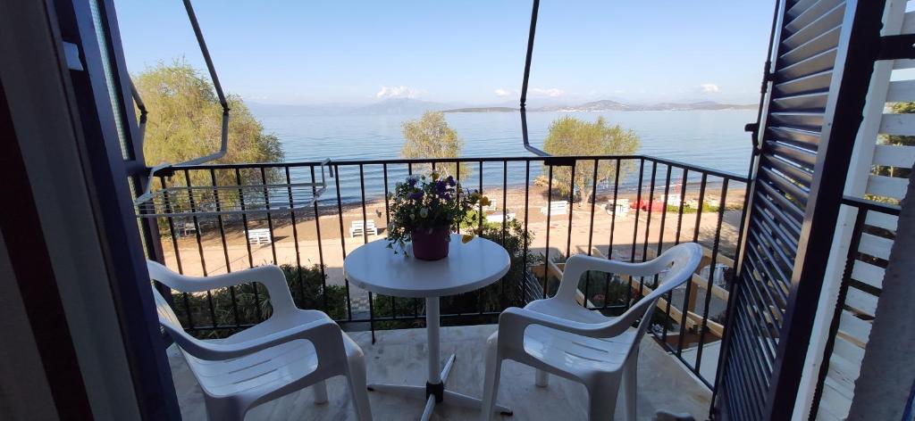 balcón con mesa, sillas y vistas al agua en Vikos Beach Apartments, en Paralía Iríon
