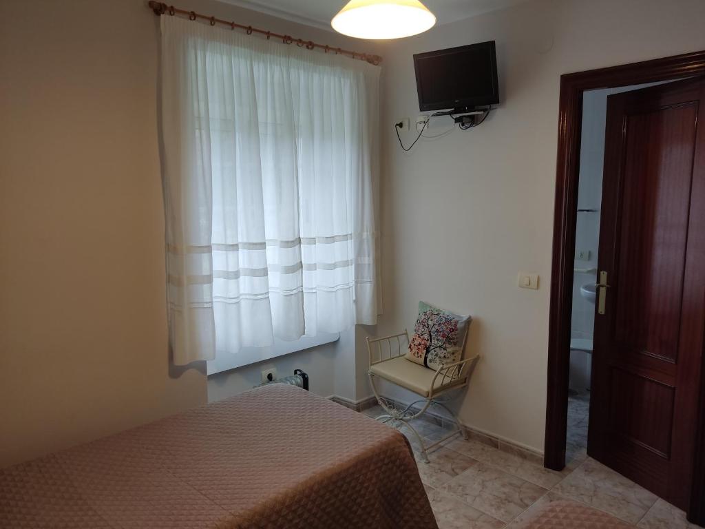 a bedroom with a bed and a chair and a window at OS MUIÑOS in Ribadeo