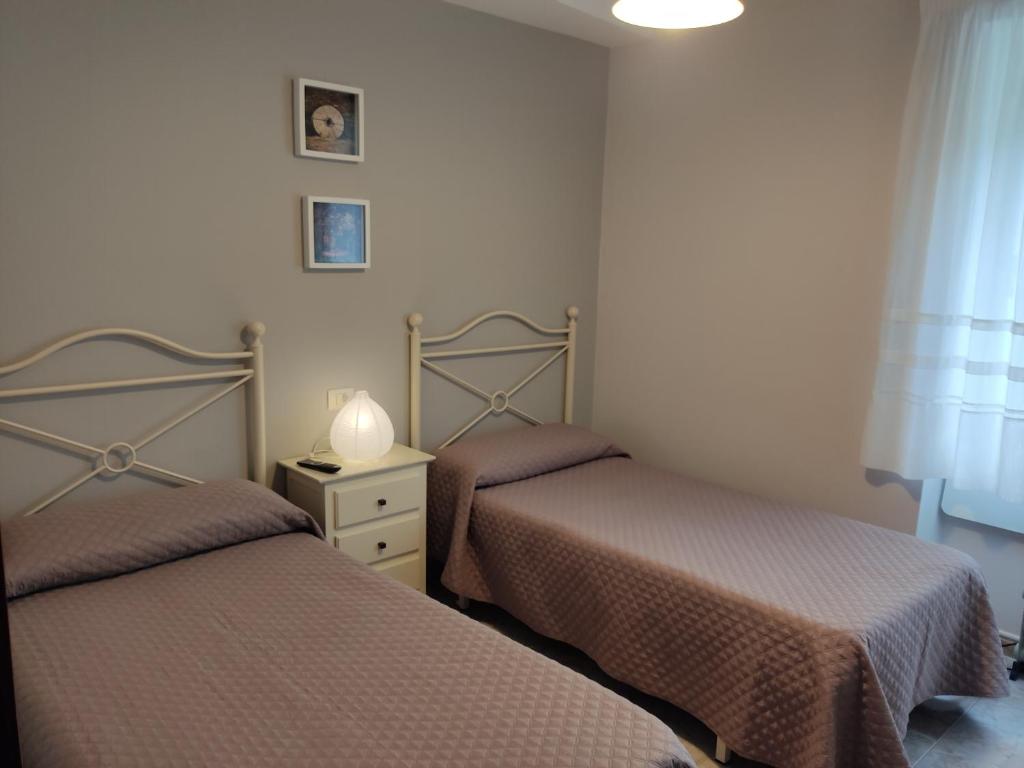 a bedroom with two beds and a table with a lamp at OS MUIÑOS in Ribadeo