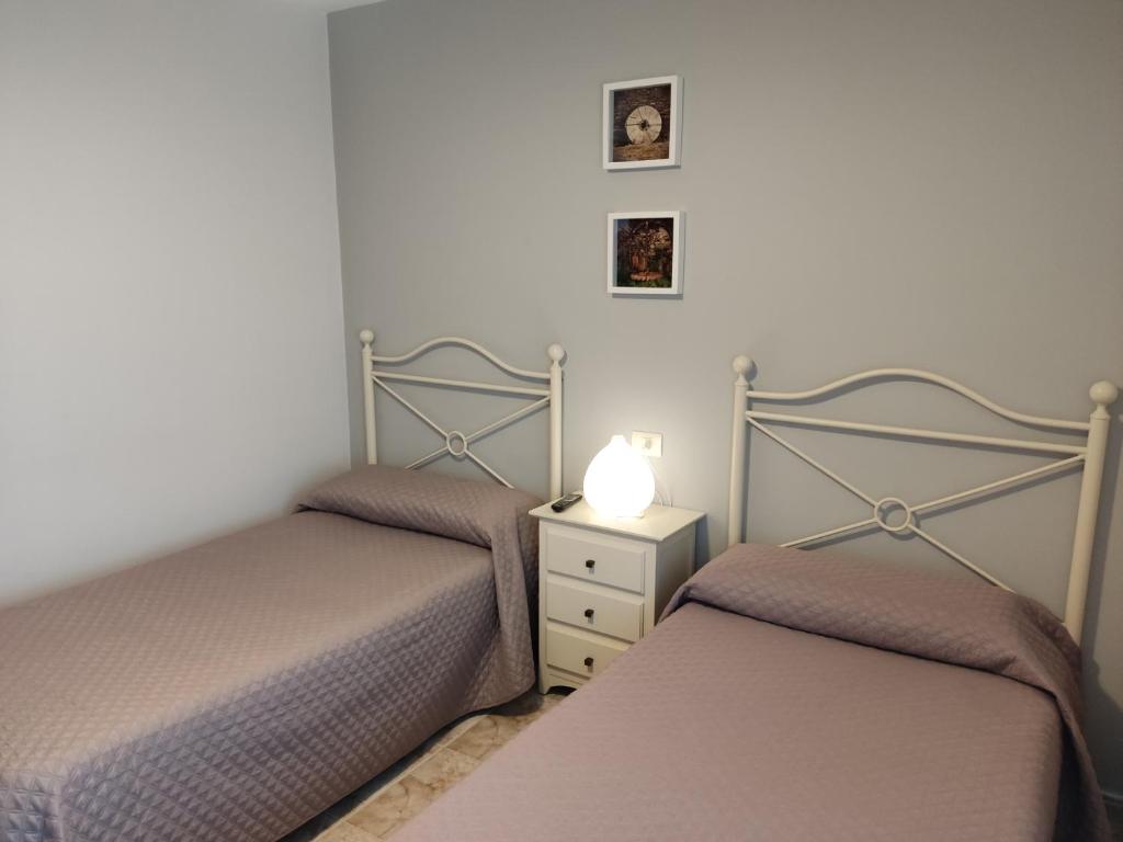 a bedroom with two beds and a night stand with a lamp at OS MUIÑOS in Ribadeo