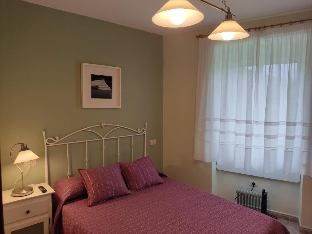 a bedroom with a bed with purple sheets and a window at OS MUIÑOS in Ribadeo
