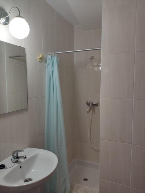 a bathroom with a sink and a shower with a shower curtain at OS MUIÑOS in Ribadeo