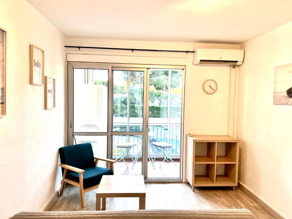 uma sala de estar com uma cadeira e uma mesa em Chaleureux Studio - Calme et Lumineux - Point Zéro - Proximité Plage et Centre Ville em La Grande-Motte