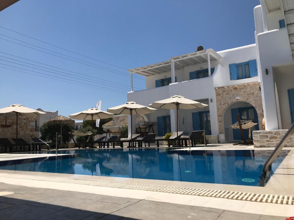 einem Pool vor einem Gebäude mit Sonnenschirmen in der Unterkunft Mer Bleu Luxury Apartments in Ampelas