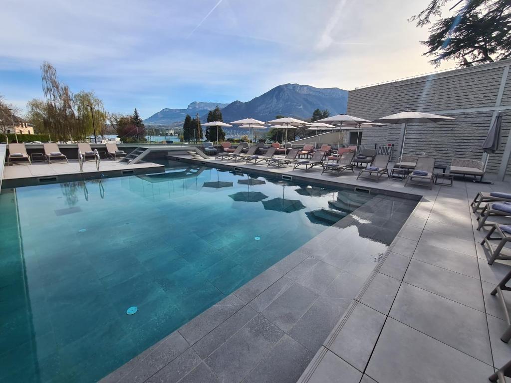 - une piscine avec des chaises longues et des parasols dans l'établissement Le Pélican, à Annecy