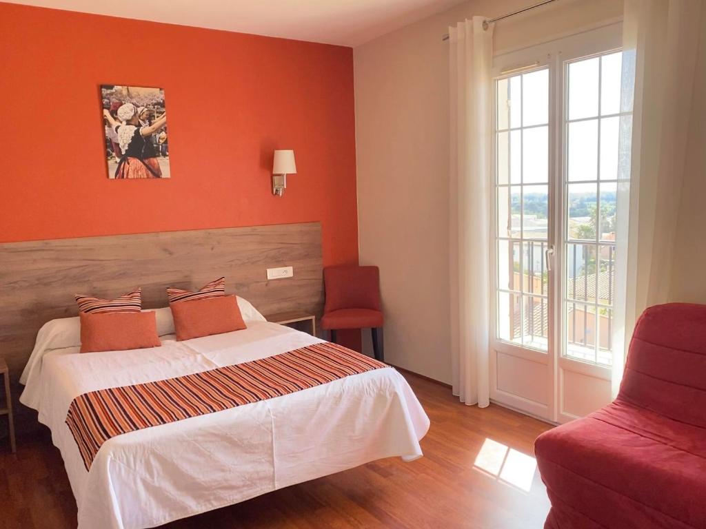 a bedroom with a bed and a red wall at Hôtel Le Belvedere in Saint-Cyprien