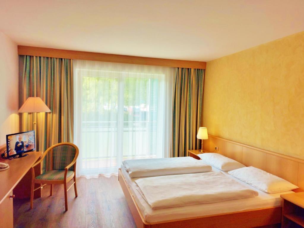 a hotel room with two beds and a desk and a window at Hotel Brenner - Stop & Go in Vipiteno