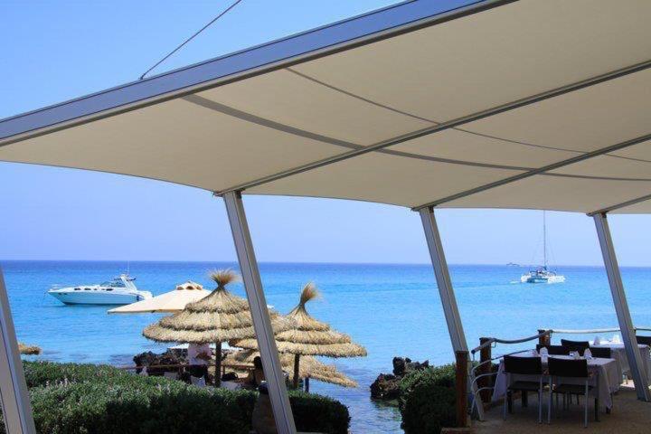 a group of tables and umbrellas on a beach at Appartement ezzouhour DAR SAMMOUD in Kelibia