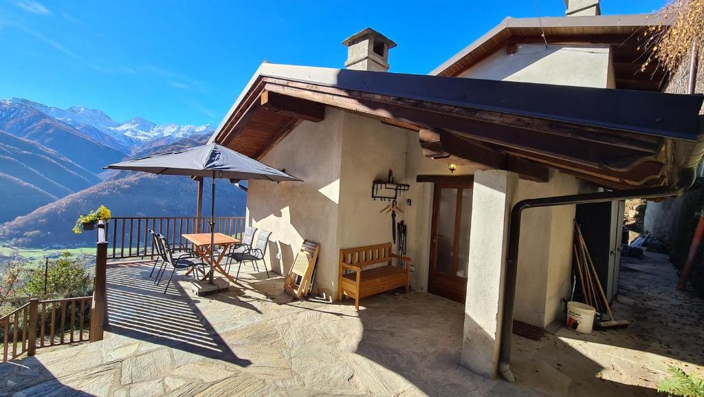 a balcony of a house with a table and an umbrella at Independent chalet with breathtaking view in Villar Pellice