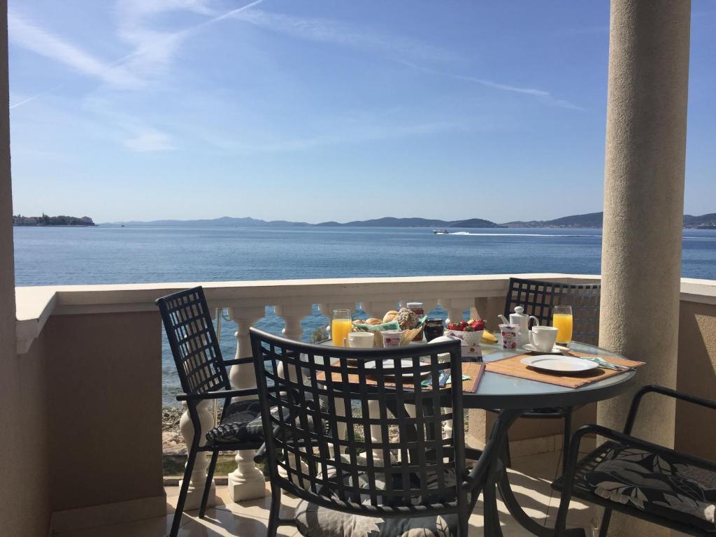 una mesa y sillas en un balcón con vistas al océano en Villa Punta, en Zadar