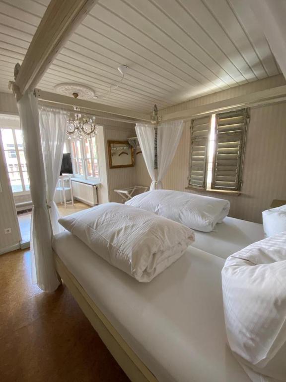 um quarto com 2 camas e almofadas brancas em Cafe einzigARTig em Rothenburg ob der Tauber