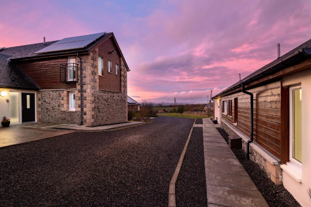 a road between two buildings with a cloudy sky at Elderburn Lodges in St. Andrews